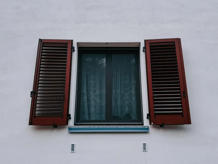 A window with open wooden shutters on the outside wall.