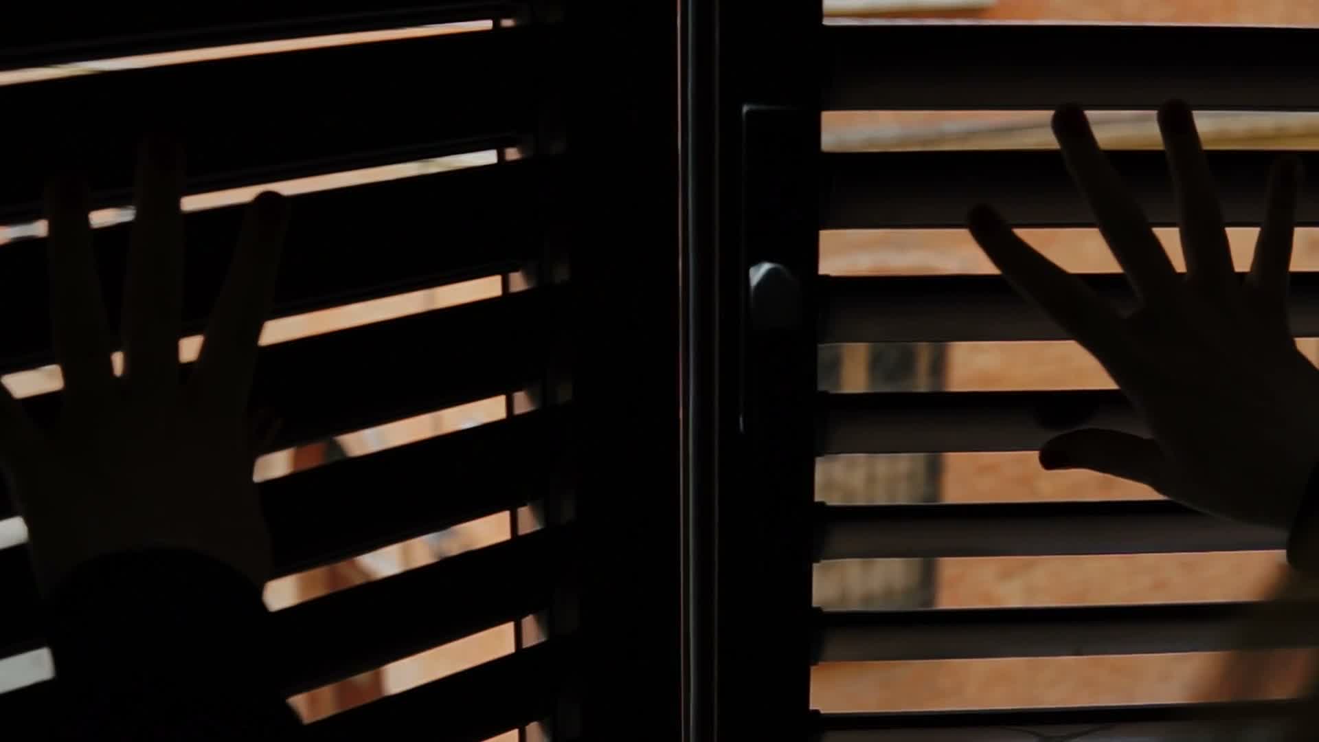 A hand beside wooden window shutters